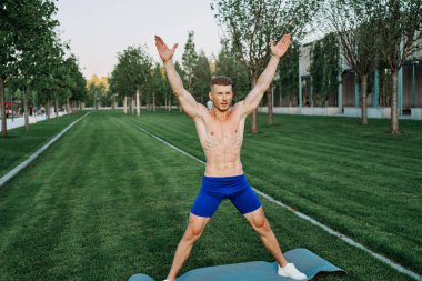 Mavi şortlu atletik adam parkta çalışıyor.