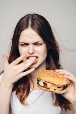 Elinde hamburger olan bir kadın. Atıştırmalık bir fast food.