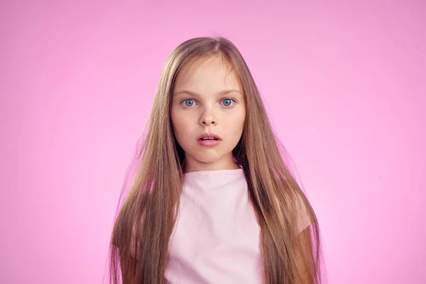 Ragazza carina con i capelli lunghi su sfondo rosa stile di vita infanzia — Foto Stock