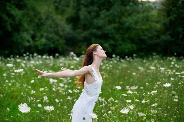 Femme gaie dans un champ avec des fleurs dans une robe blanche dans la nature — Photo