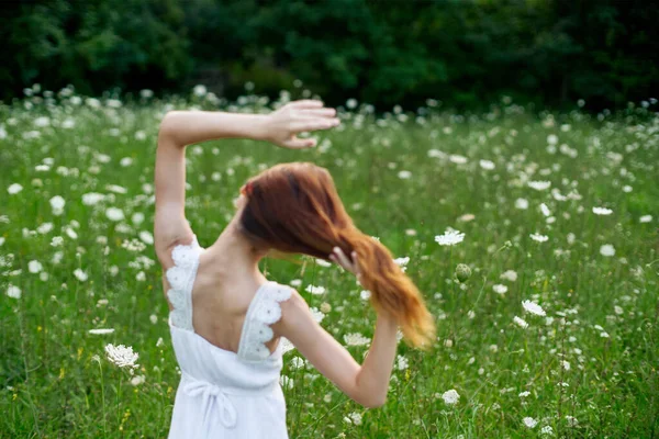 Woman in white dress in a field of flowers walk freedom — Stock Photo, Image