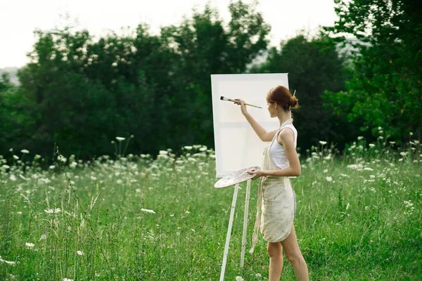 Kadın sanatçı, doğa manzarasında sehpada resim yapar. — Stok fotoğraf