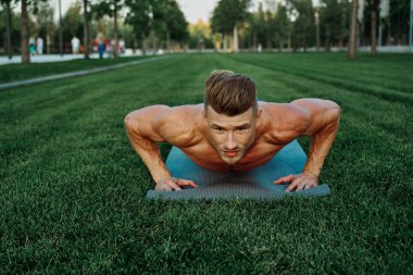 Spor kaslı adam parkta spor yapıyor.
