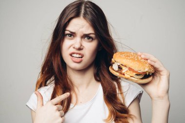 Elinde hamburger olan bir kadın. Atıştırmalık bir fast food.