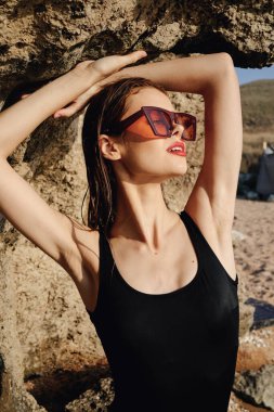 Siyah mayolu güzel bir kadın güneş gözlüğü takıyor.
