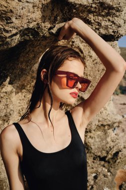 Siyah mayo giymiş kadın güneş gözlüğü takıyor.