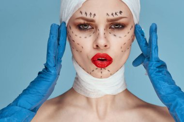 Mavi eldivenli bir kişi kırmızı dudaklı ameliyat yüzü gençleştirme mavi arka plan