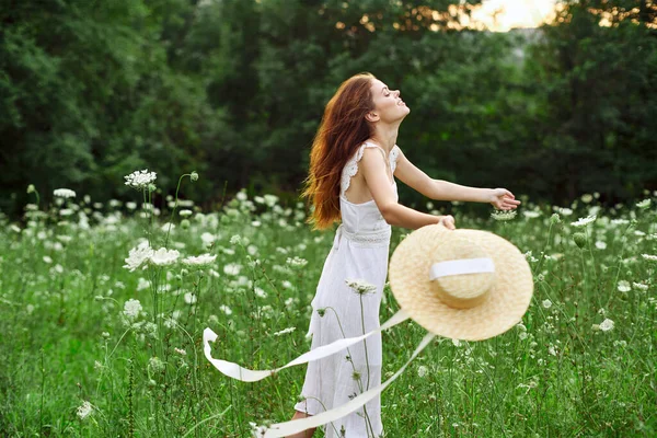 Beyaz şapkalı kadın elinde çiçekler, doğa yürüyüşü. — Stok fotoğraf