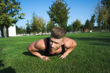 Parktaki spor salonunda vücudunu şişiren atletik adam. Temiz hava.