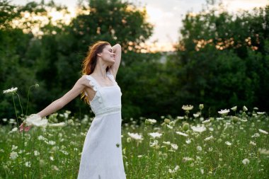 Beyaz elbiseli, kır çiçekli kadın. Güneş doğası özgürlüğü.