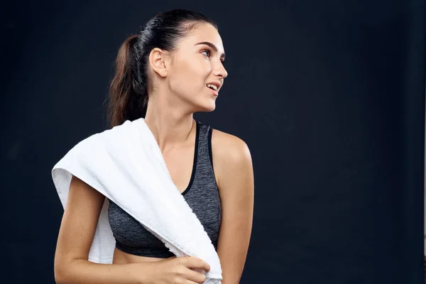 Mulher atlética com toalha branca ginásio figura slim fundo escuro — Fotografia de Stock