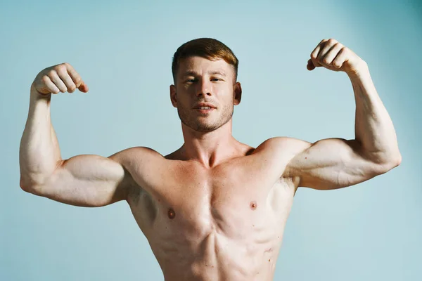 健美运动员，肌肉发达，呈蓝色背景 — 图库照片