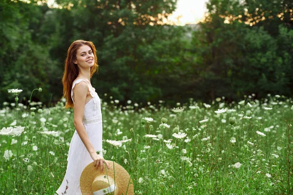 Mulher de vestido branco e chapéu em um campo com estilo de vida de flores — Fotografia de Stock