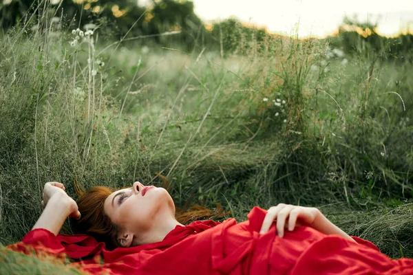 Jolie femme en robe rouge se trouve sur l'herbe paysage de liberté — Photo