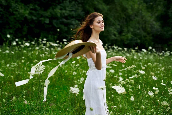 Kvinna i vit klänning hatt natur fält blommor — Stockfoto