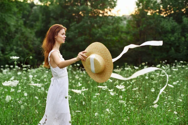 Жінка в білій сукні і капелюсі в полі з квітковим способом життя — стокове фото