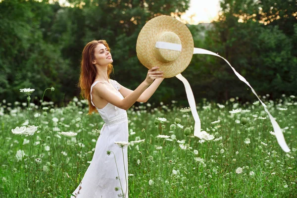 Mujer en vestido blanco y sombrero en un campo con estilo de vida de flores — Foto de Stock