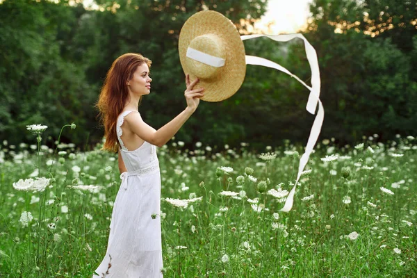 Kvinna i vit klänning och hatt i ett fält med blommor livsstil — Stockfoto