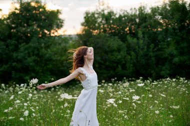 Beyaz elbiseli kadın dans doğası yaz pozu veriyor.