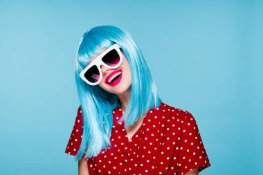 Mavi peruklu, güneş gözlüklü, neşeli bir kadın.