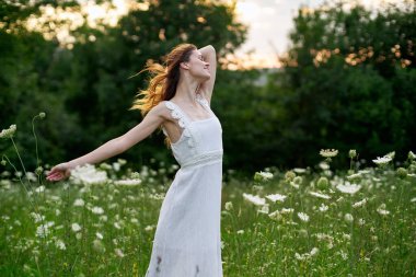 Beyaz elbiseli, kır çiçekli kadın. Güneş doğası özgürlüğü.