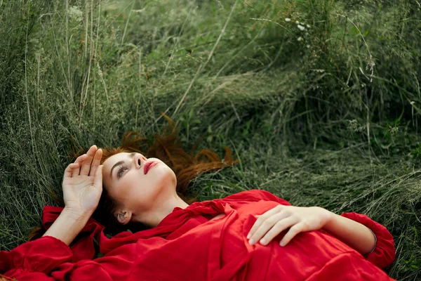穿着红衣服的漂亮女人躺在草地上 — 图库照片