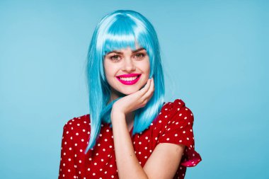 Mor peruklu neşeli kadın mavi arka plan pozu veriyor.