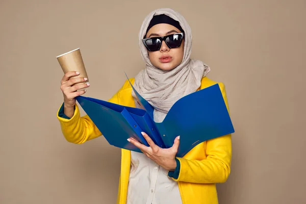 Vrouw in zonnebril in hijab een kopje koffie beige achtergrond — Stockfoto