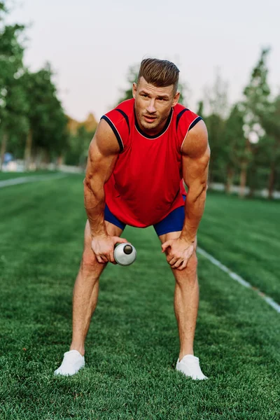 Веселый спортсмен в парке на зеленой траве делает упражнения — стоковое фото