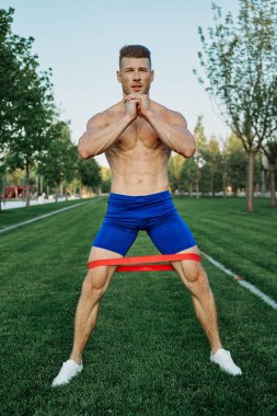 Atletik adam parkta koşma egzersizi yapıyor.