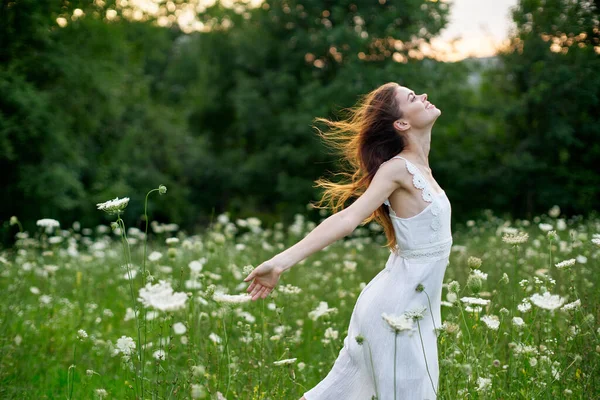 Kvinna i vit klänning i ett fält av blommor gå frihet — Stockfoto