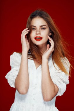 Kırmızı dudaklı neşeli kızıl saçlı kadın. Beyaz elbise. Kırmızı arka plan.