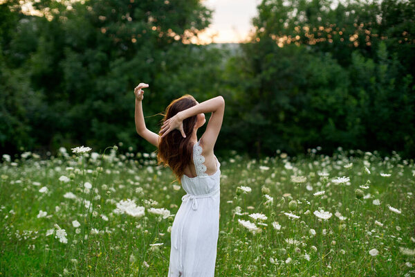 Woman in a white dress in a field on nature flowers freedom summer. High quality photo