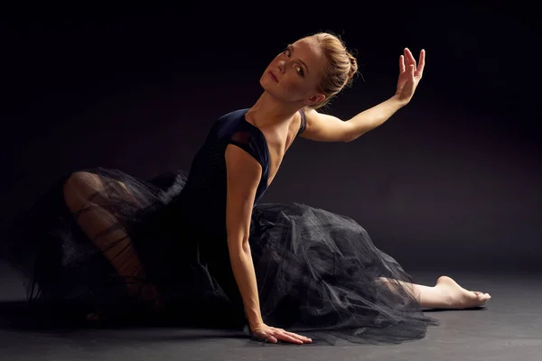 Csinos nő egy fekete ruha tánc divat gyakorlat sötét háttér — Stock Fotó