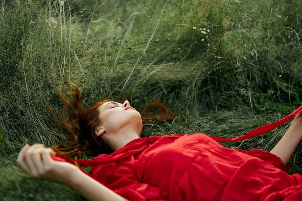 Femme en robe rouge couché sur l'herbe air frais nature romance — Photo