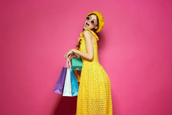 Блискуча жінка з різнокольоровими сумками, що позують рожевий фон — стокове фото