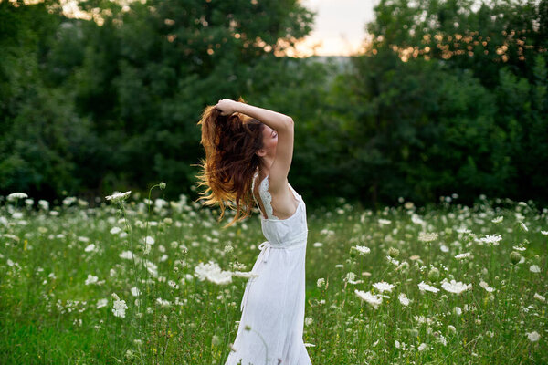 Woman in a white dress in a field on nature flowers freedom summer. High quality photo