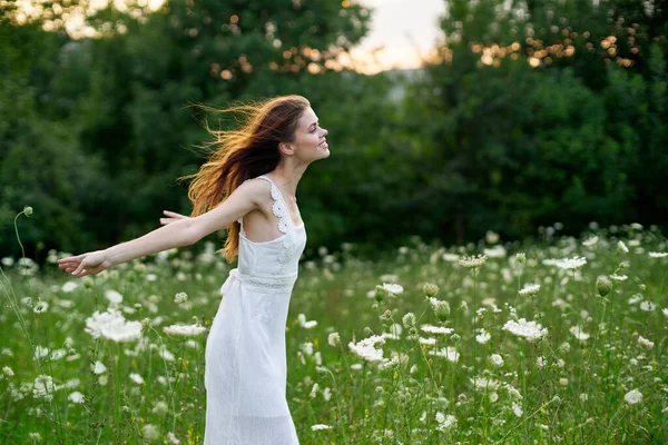 Çiçek tarlasında beyaz elbiseli bir kadın özgürce yürüyor. — Stok fotoğraf