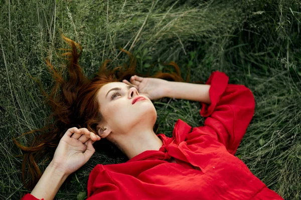 Woman in red dress lies on the grass charm freedom — Stock Photo, Image