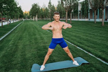 Mavi şortlu atletik adam parkta çalışıyor.