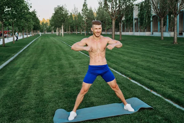 Mavi şortlu atletik adam parkta çalışıyor.