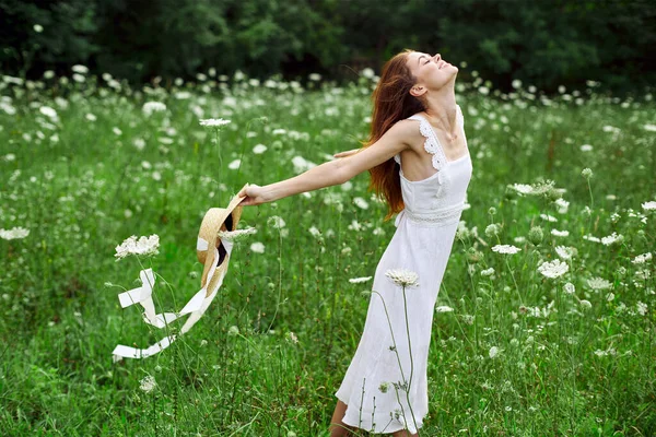 Mujer en vestido blanco sombrero sosteniendo flores naturaleza paseo — Foto de Stock