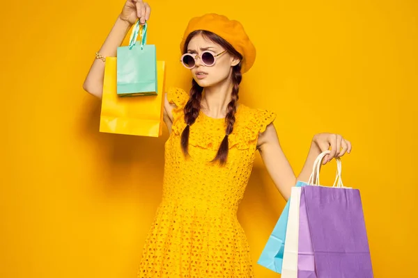 Hezká žena s pestrobarevnými tašky pózovat žluté pozadí — Stock fotografie