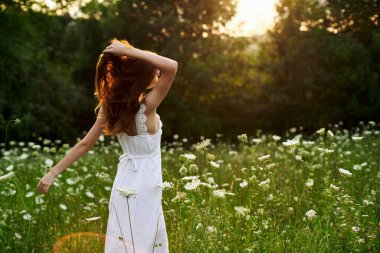 Beyaz elbiseli, kır çiçekli kadın. Güneş doğası özgürlüğü.