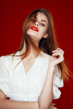 Kırmızı dudaklı neşeli kızıl saçlı kadın. Beyaz elbise. Kırmızı arka plan.