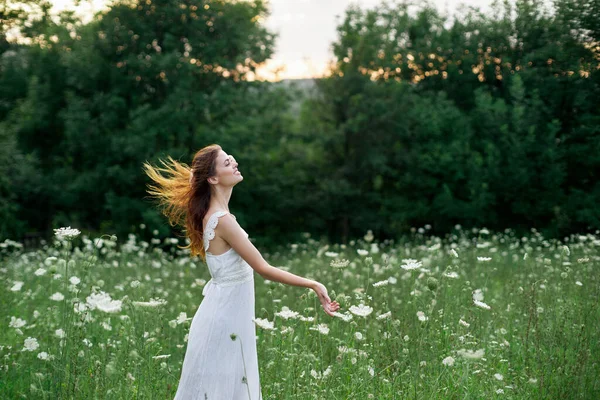 Mulher em um vestido branco em um campo na natureza flores liberdade verão — Fotografia de Stock