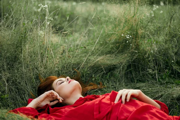 Jolie femme en robe rouge se trouve sur l'herbe paysage de liberté — Photo