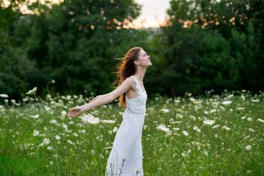Beyaz elbiseli, çiçekli, tarlada neşeli bir kadın.