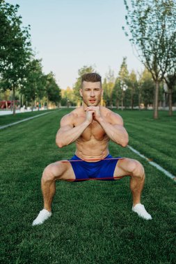 Atletik adam parkta koşma egzersizi yapıyor.