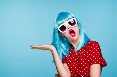 Mavi peruklu, güneş gözlüklü, neşeli bir kadın.